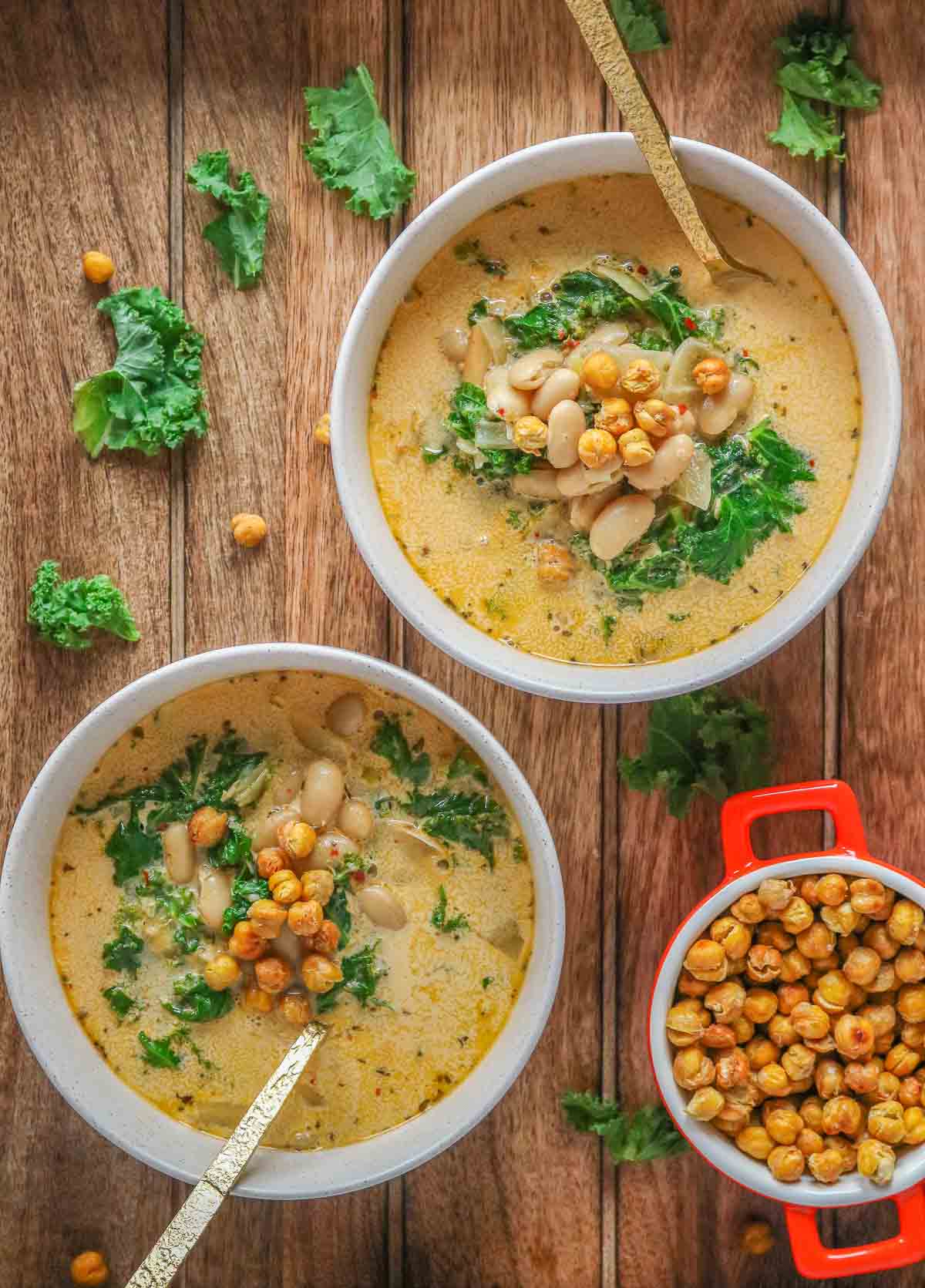 Two bowls of bean and kale soup with crispy chickpeas.