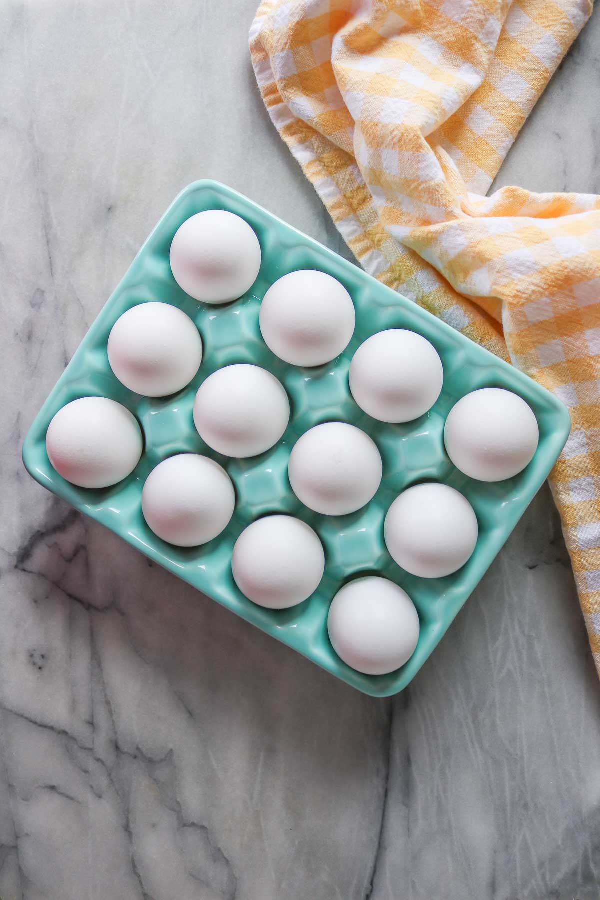 Twelve whole eggs in a glass carton.