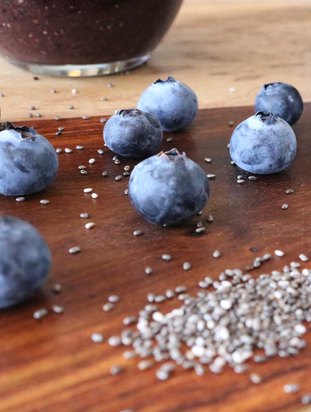 Fresh blueberries and chia seeds on a wooden board.