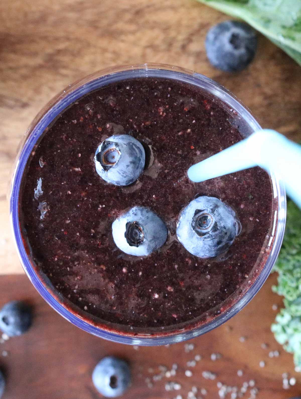 Overhead shot of a glass of blueberry kale smoothie.