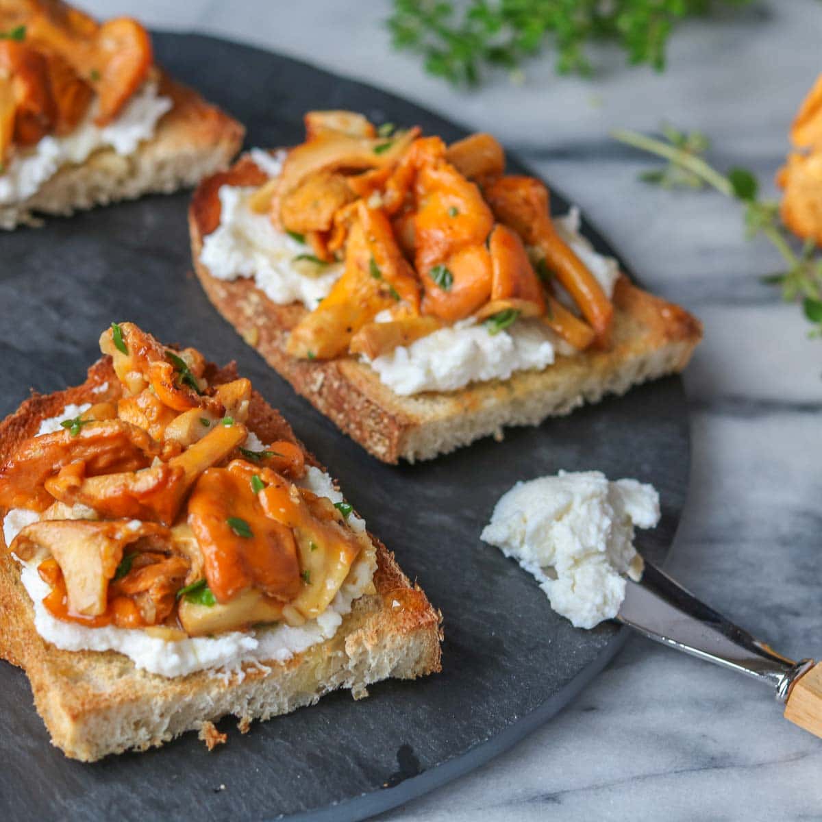 Chanterelle mushroom crostini next to a spreader with ricotta on it.