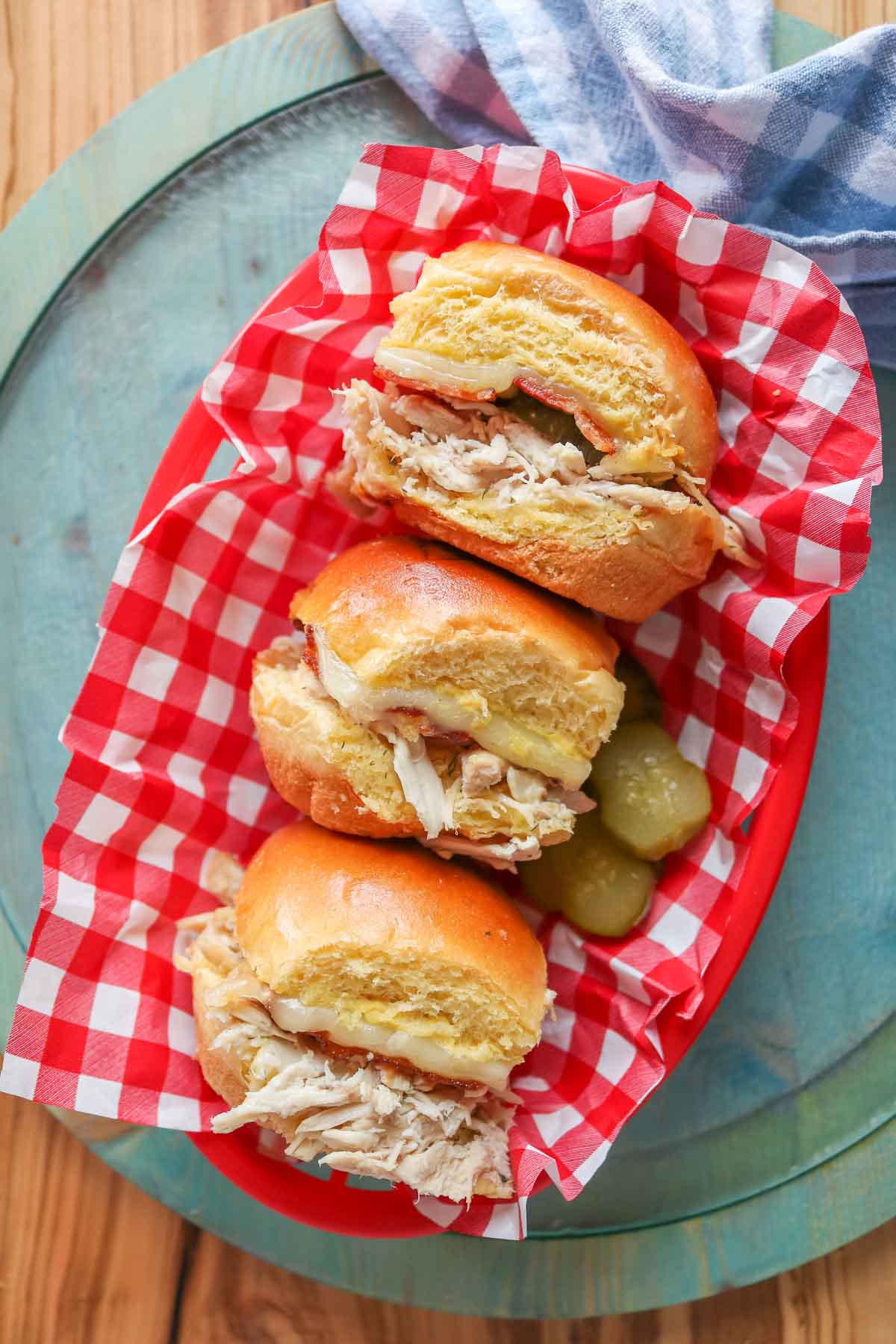 Three chicken bacon ranch sliders in a checkered paper-covered basket.