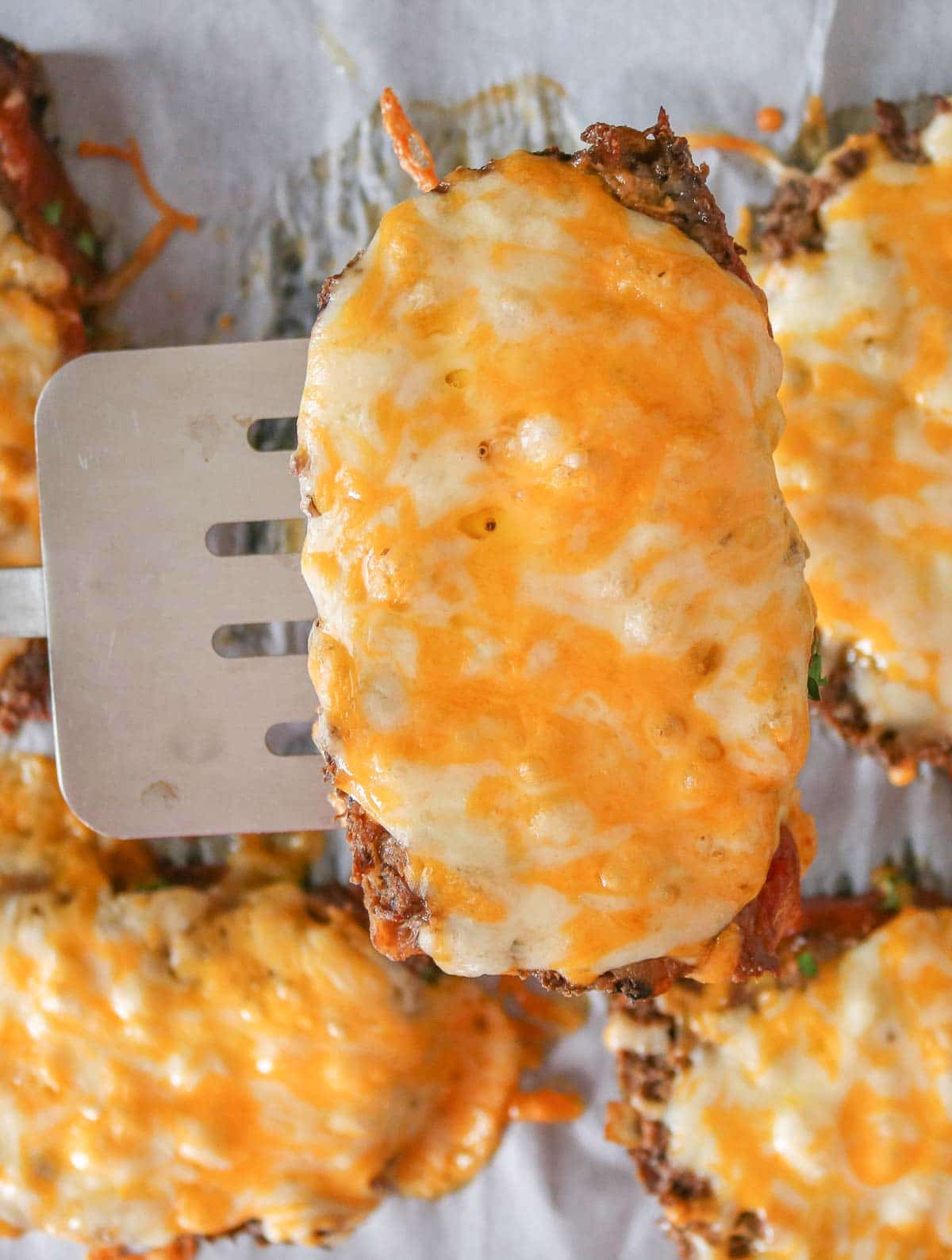 Slice of cheesy meatloaf on a spatula.