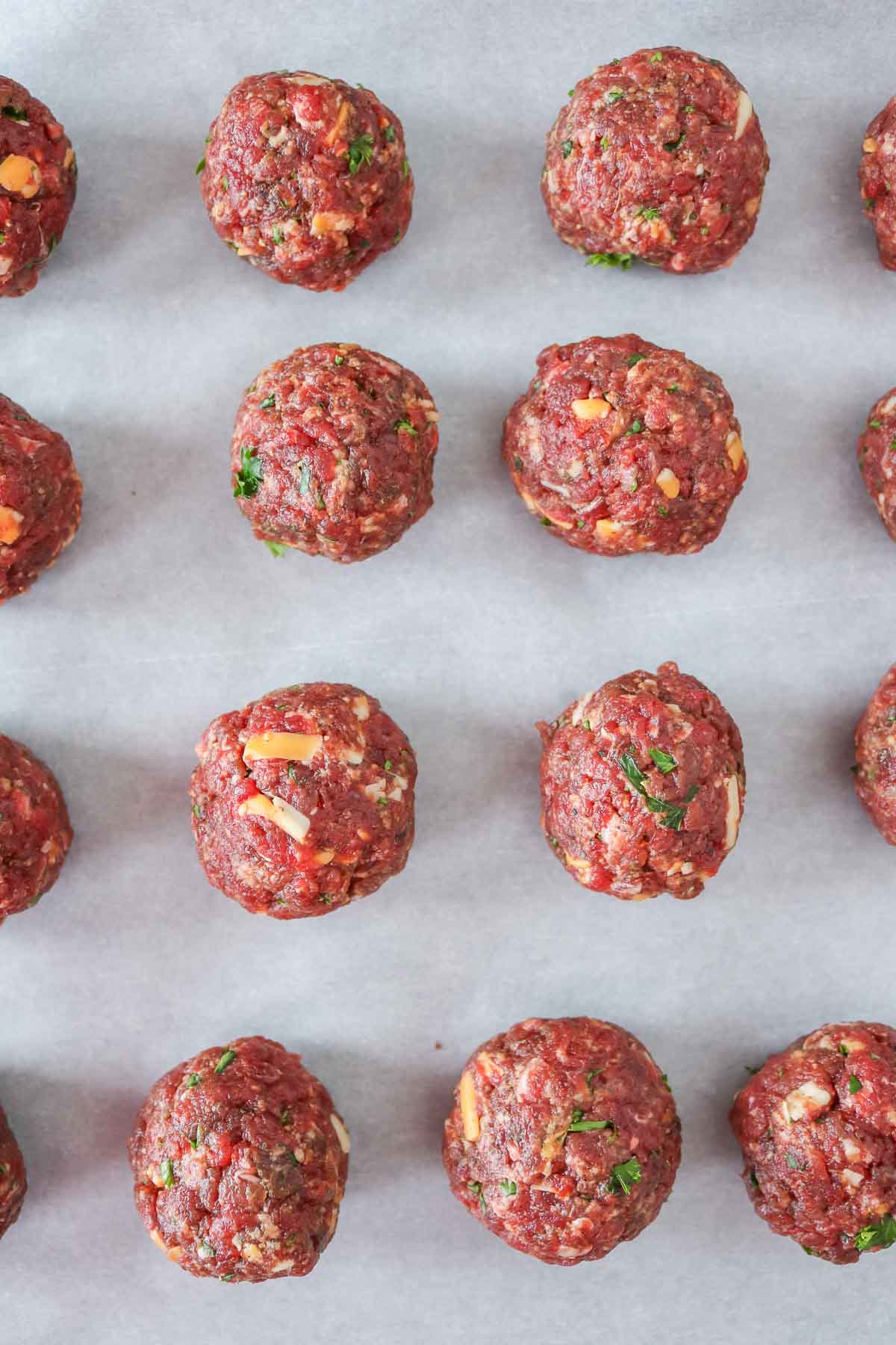 Moose meatballs on a parchment paper-lined sheet pan before cooking.