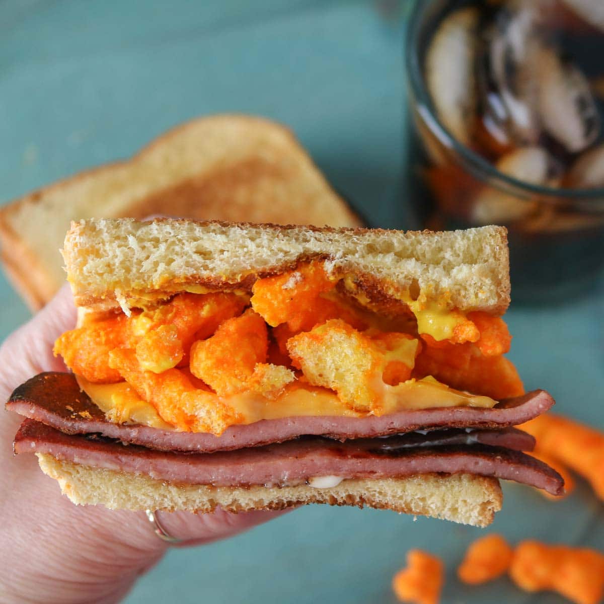 Hand holding one half of a fried bologna sandwich.