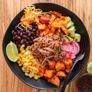 Pulled pork rice bowl with toppings and drizzled with barbecue sauce.