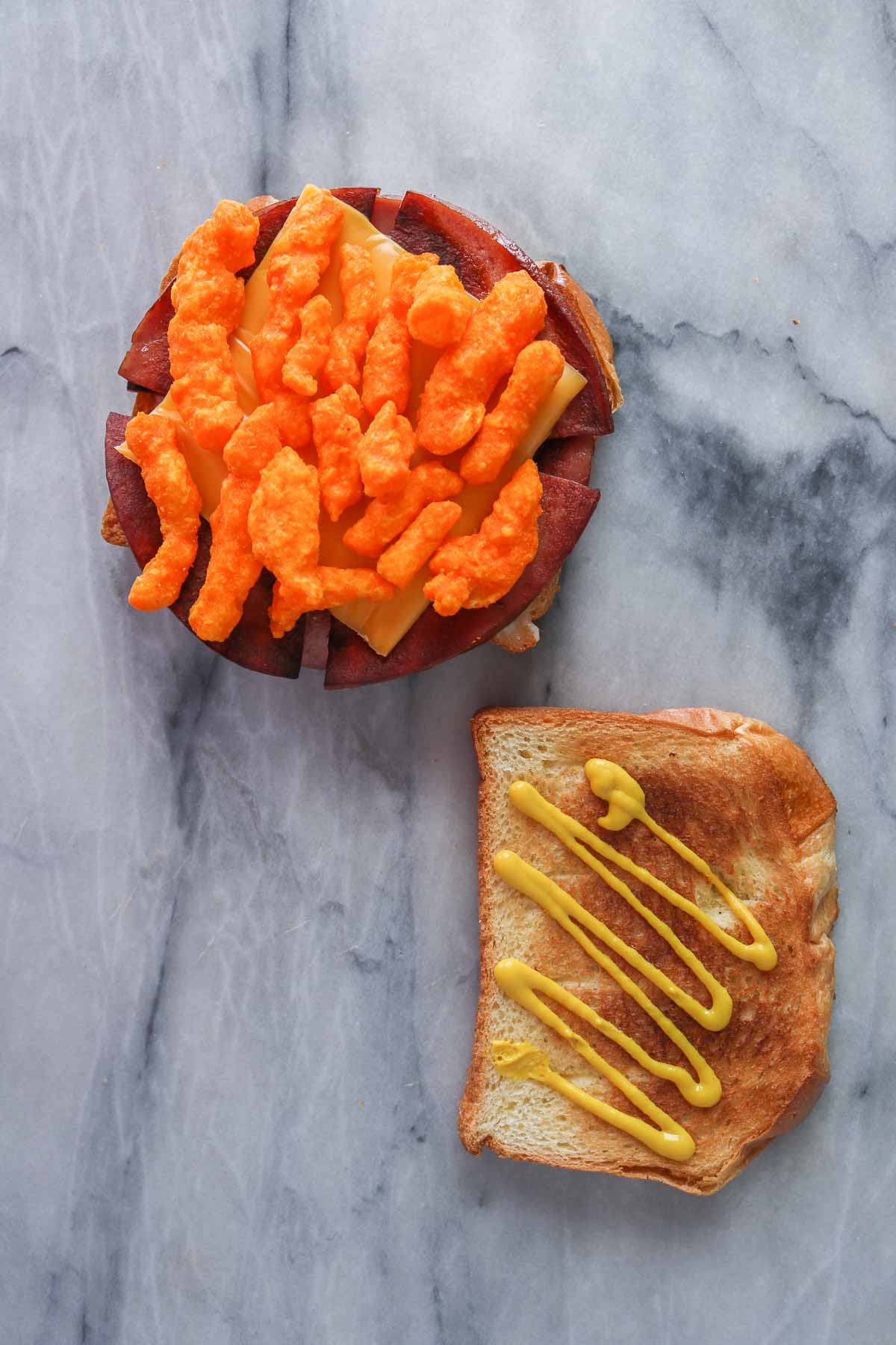 Assembling a fried bologna sandwich with crunchy cheese puffs.