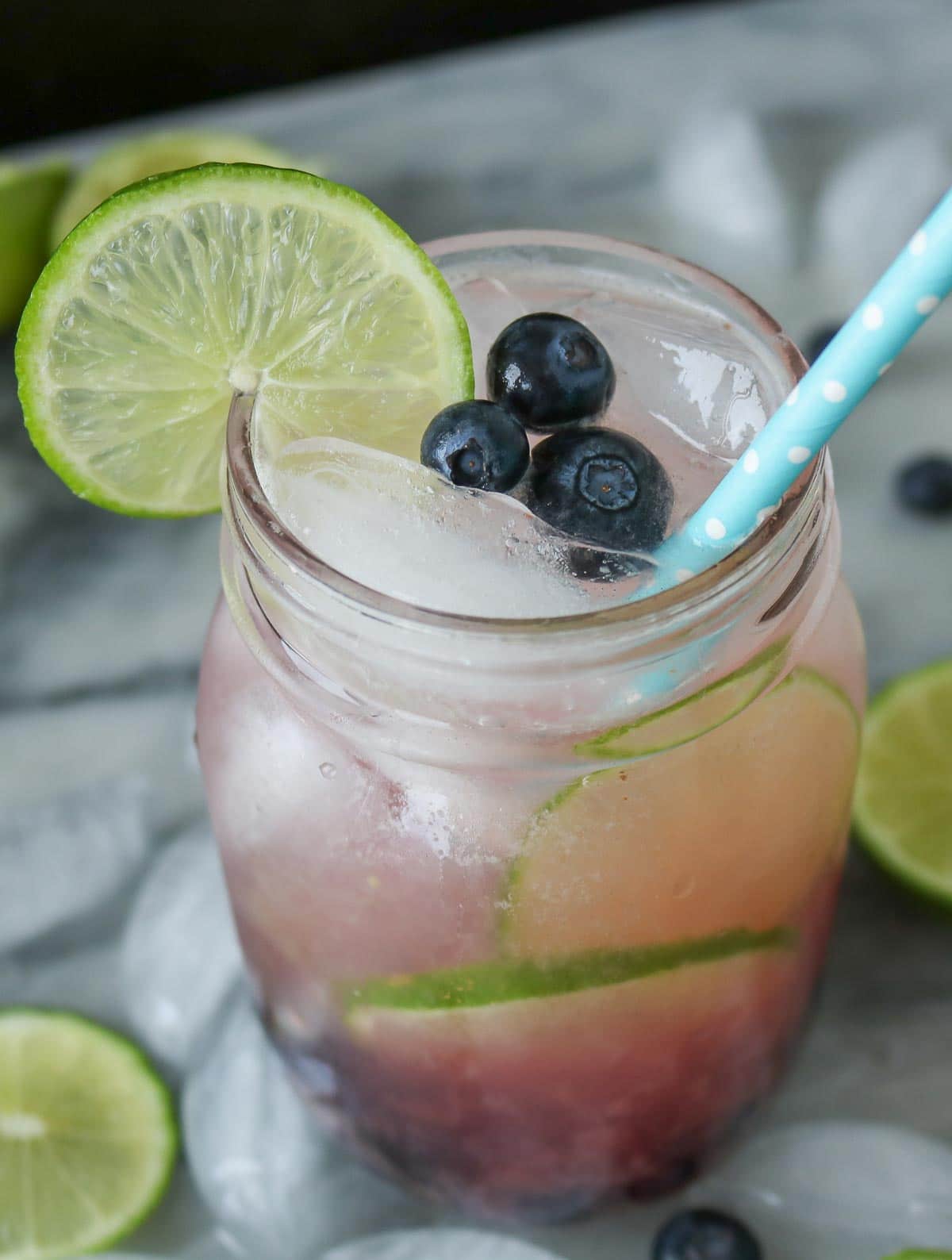 Blueberry and lime mocktail in a glass jar garnished with blueberries and lime.