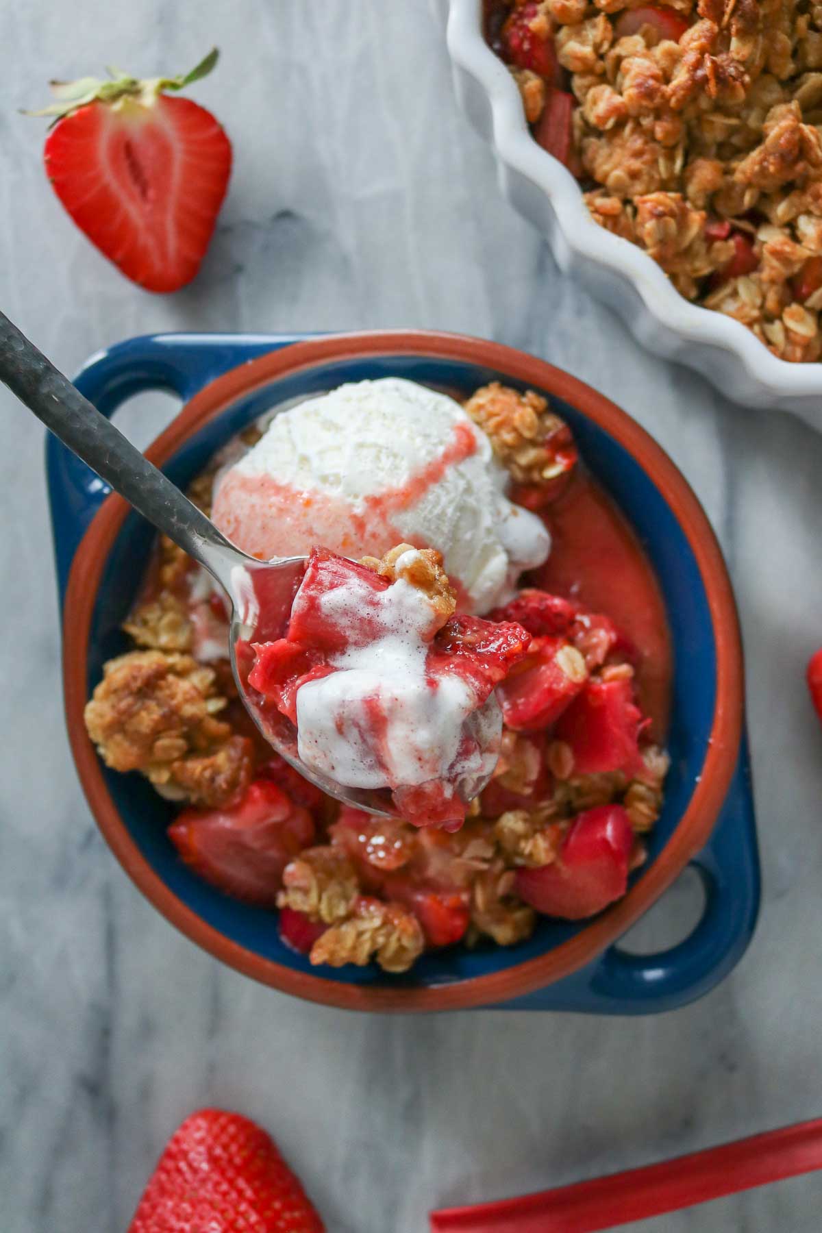 Spoonful of fruit crisp and ice cream from a dish.