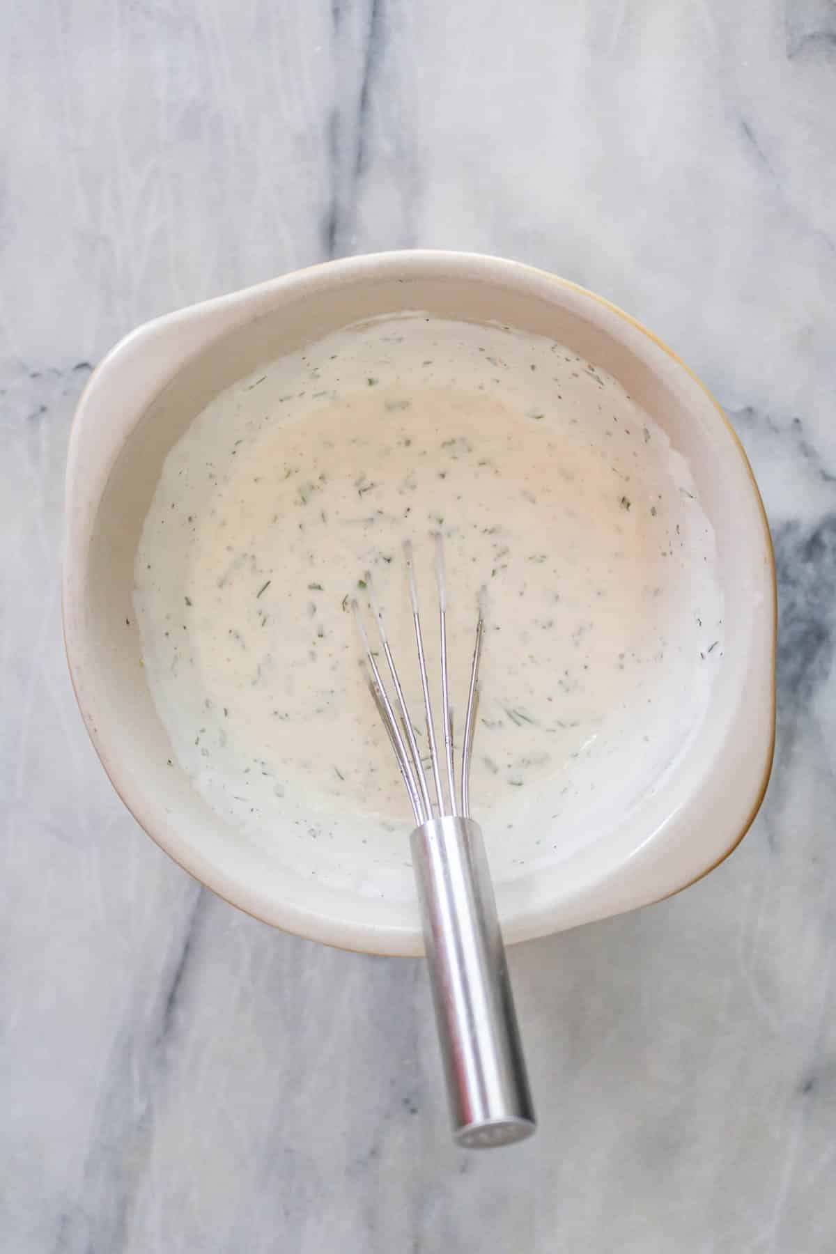 Creamy dressing in a small bowl with a whisk.