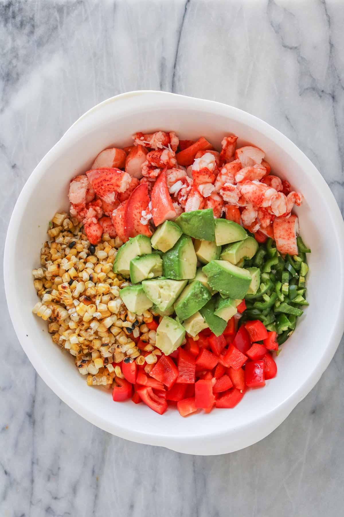 Lobster pasta salad ingredients in a mixing bowl before being mixed together.