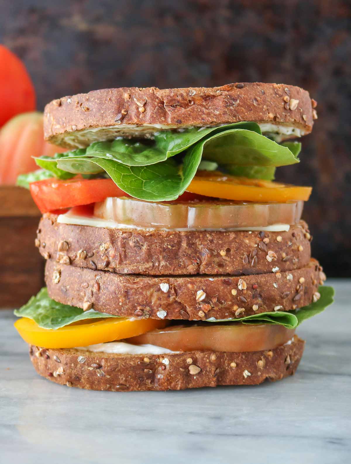 Stack of two toasted heirloom tomato sandwiches.