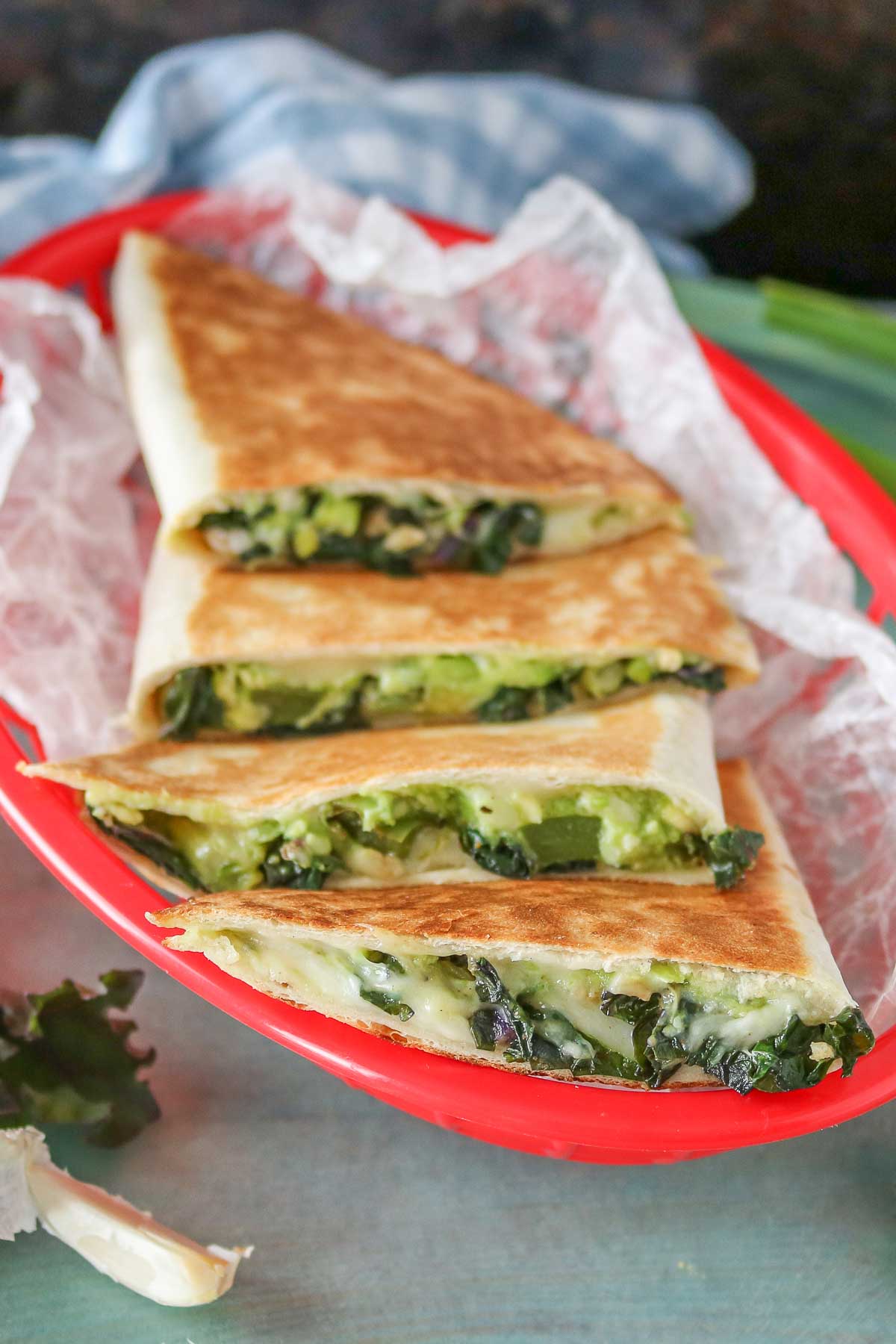 Avocado and veggie quesadillas in a wax paper-lined red basket.