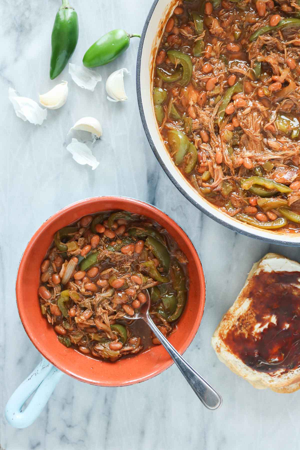 Pulled pork and beans, some in a serving bowl and some in a pan.