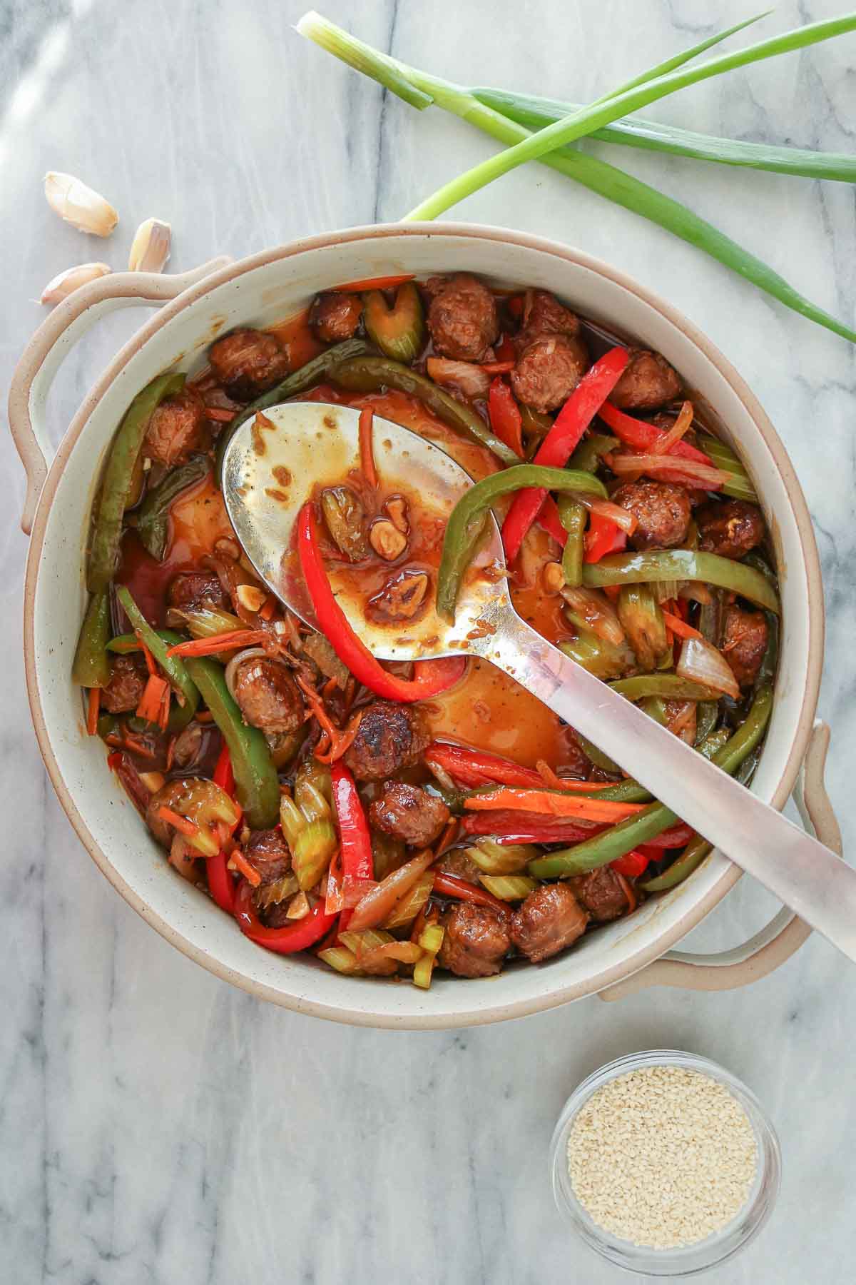 Serving spoon resting in a partially filled dish of stir-fry.