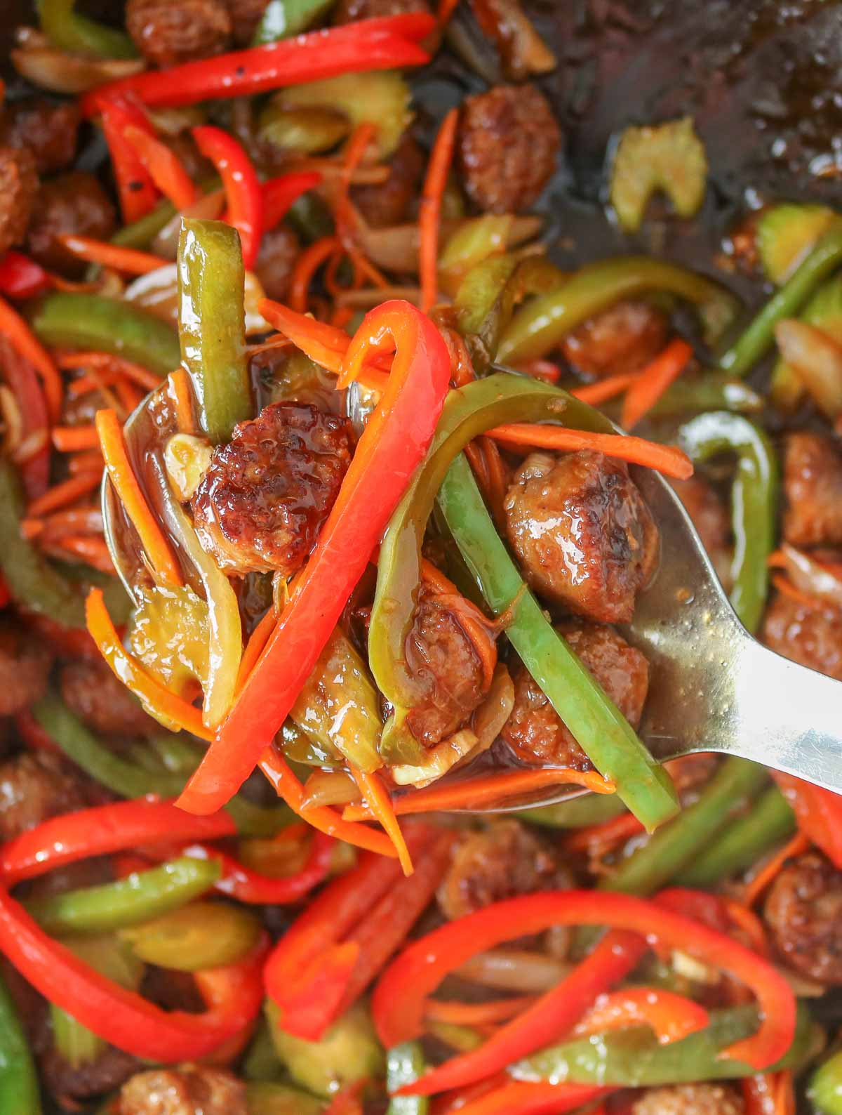 Serving spoon scooping up stir-fry from a wok.