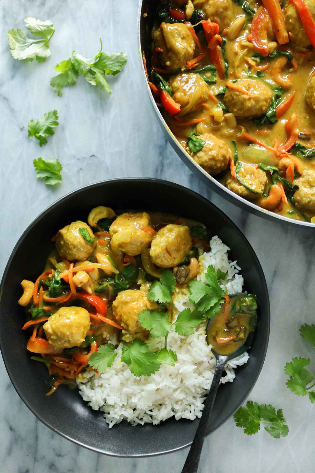 Turkey meatballs with curry sauce, some in a pan and more in a bowl with rice.