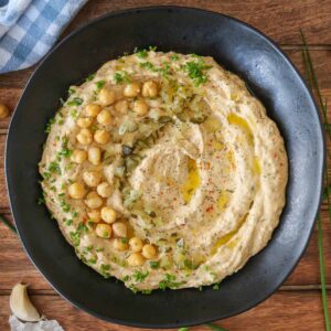 Bowl of dill pickle hummus with toppings.