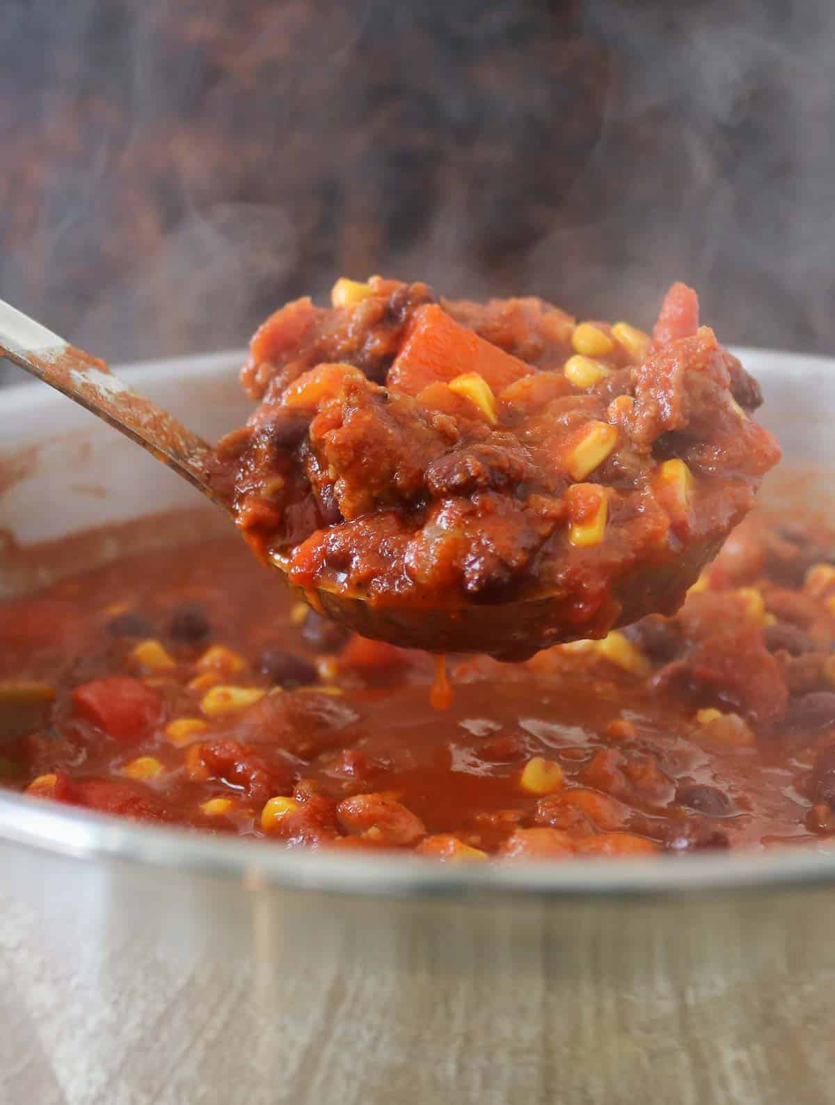 Steaming ladle of chili from a pot.
