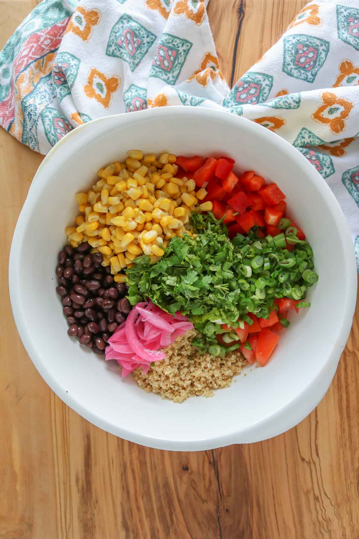 Quinoa salad ingredients in a bowl before being mixed together.