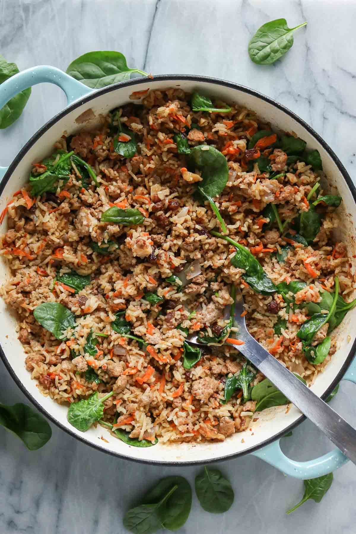 Ground chicken, rice and vegetables in a pan with a serving spoon.