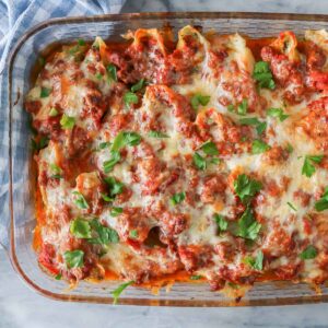 Stuffed shells in a baking dish garnished with parsley.