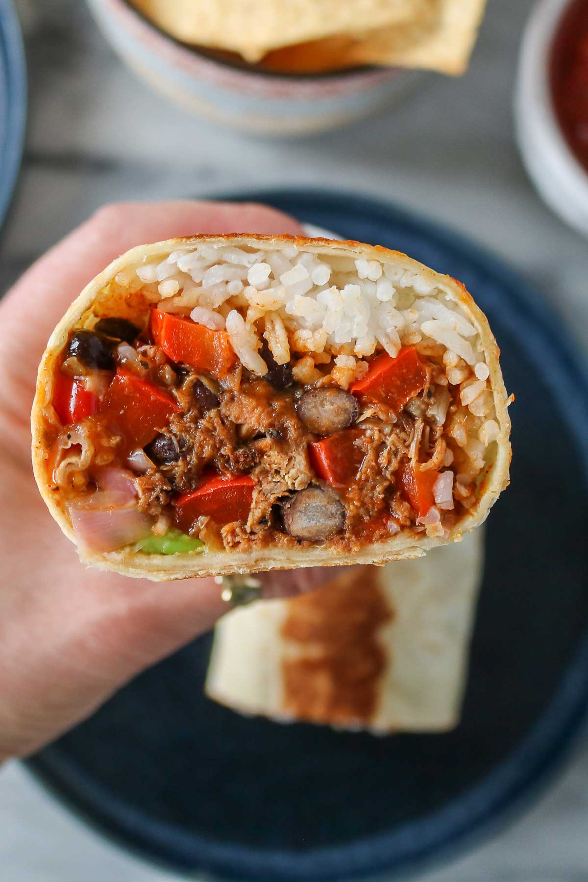 Hand holding a pulled pork burrito.