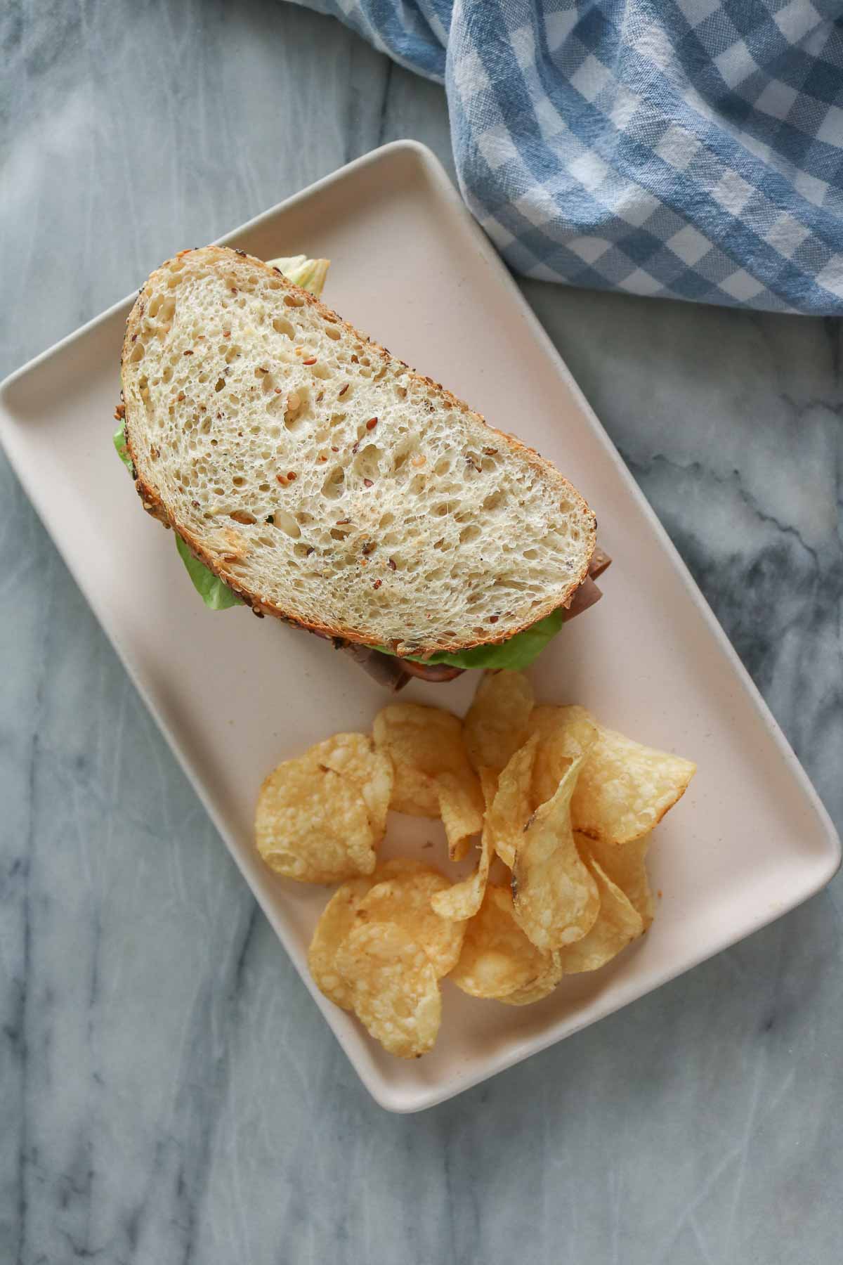 Overhead shot of a sandwich and potato chips on a plate.