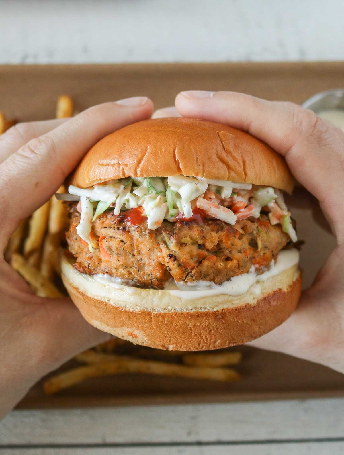 Two hands holding a buffalo chicken burger.