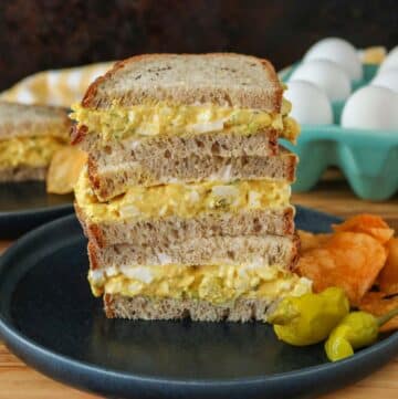 Stack of three curried egg salad sandwich halves on a plate.