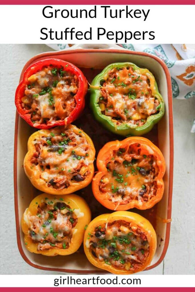 Six baked stuffed peppers in a baking dish garnished with chives.