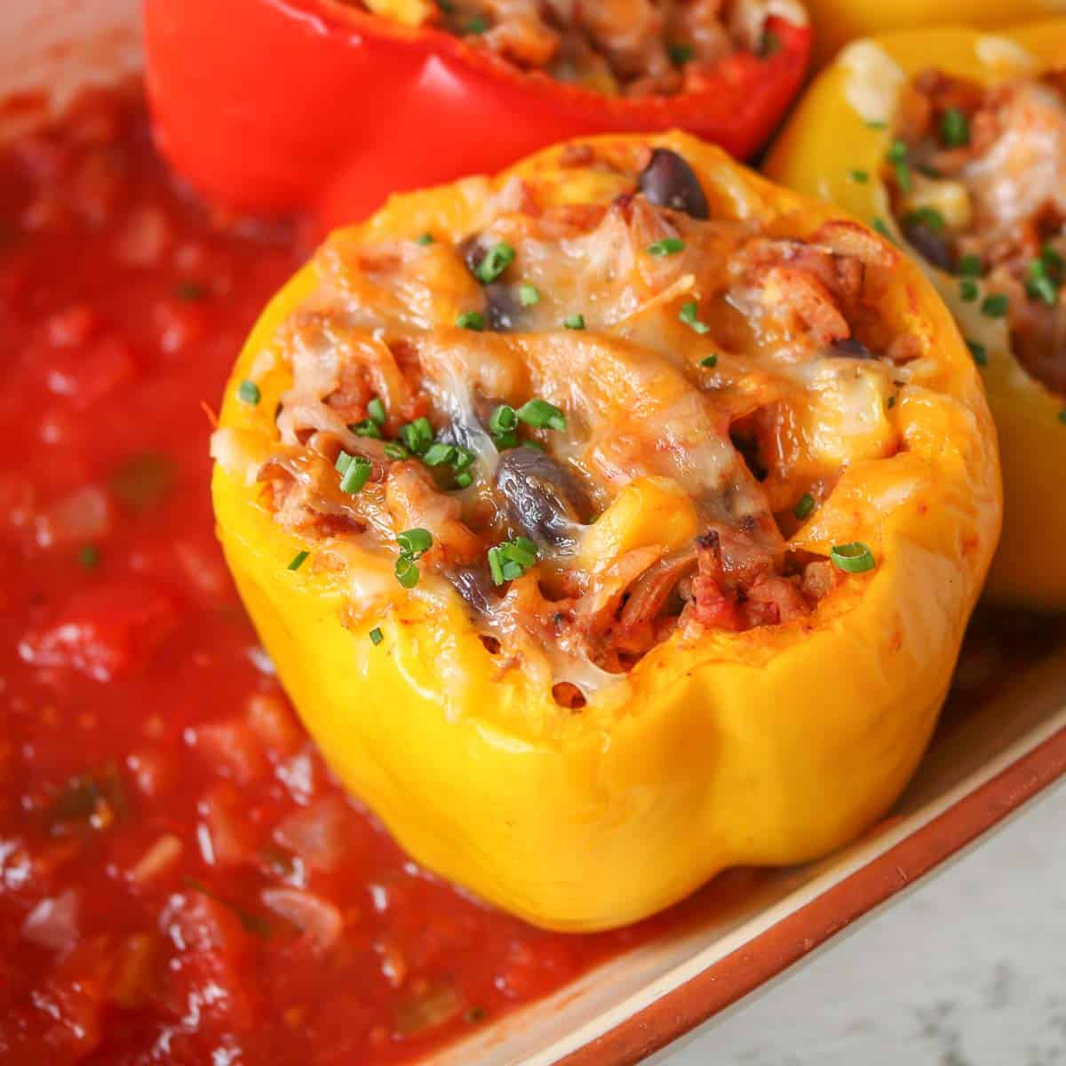 Close-up of a stuffed pepper in a baking dish garnished with chives.
