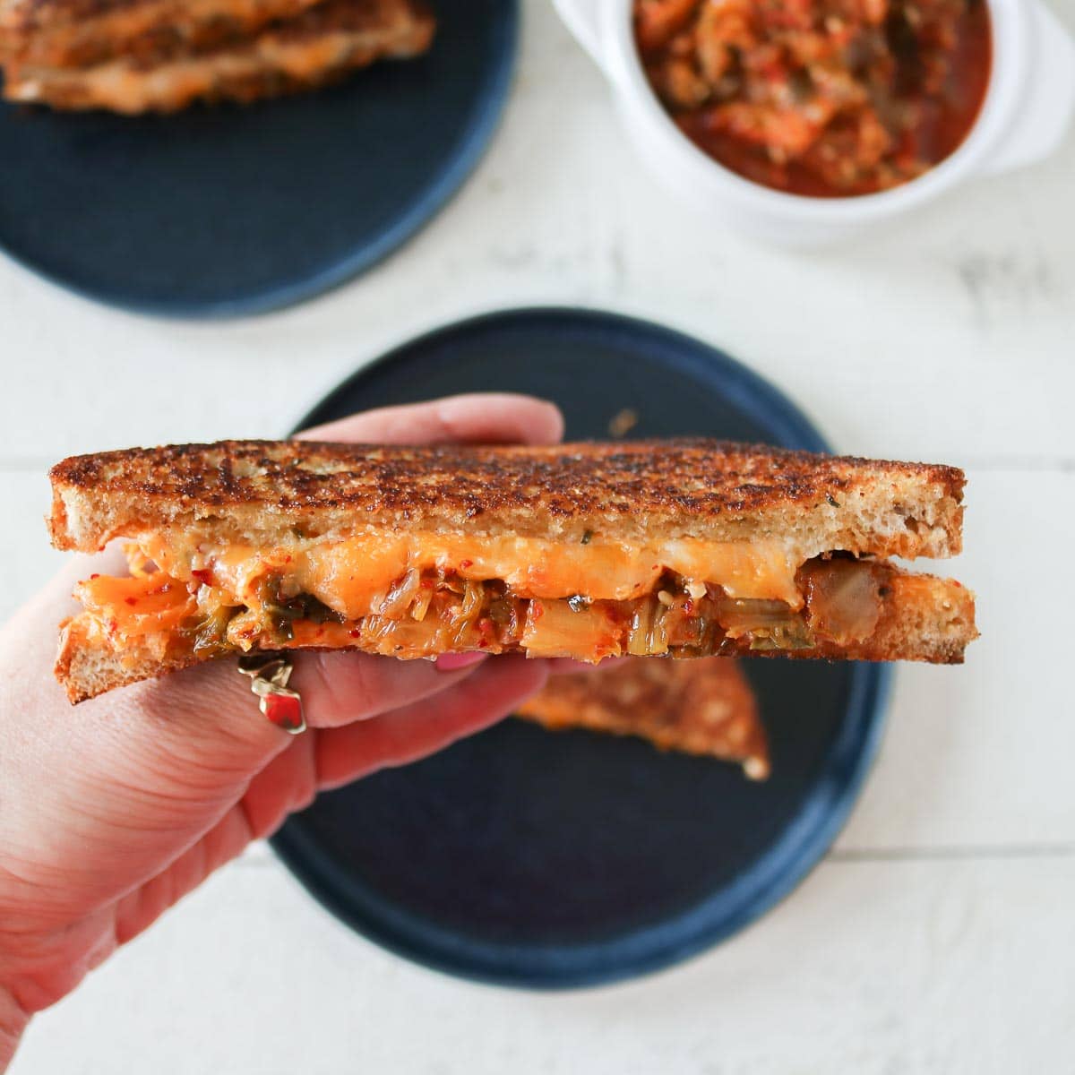 Hand holding a kimchi grilled cheese sandwich.