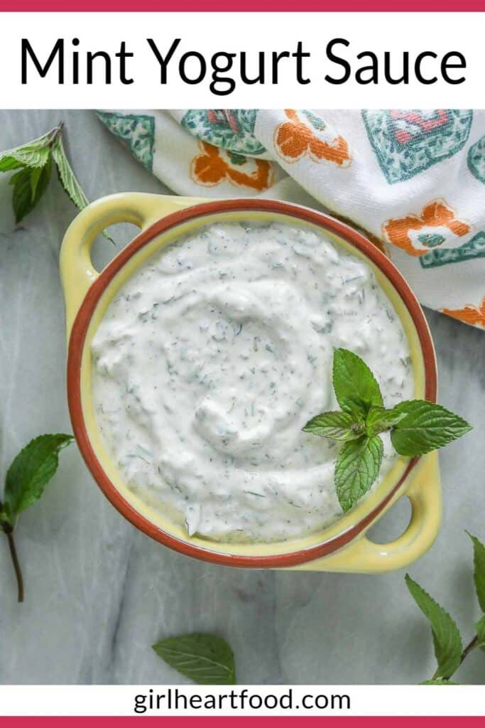 Mint yogurt sauce in a yellow bowl garnished with mint.