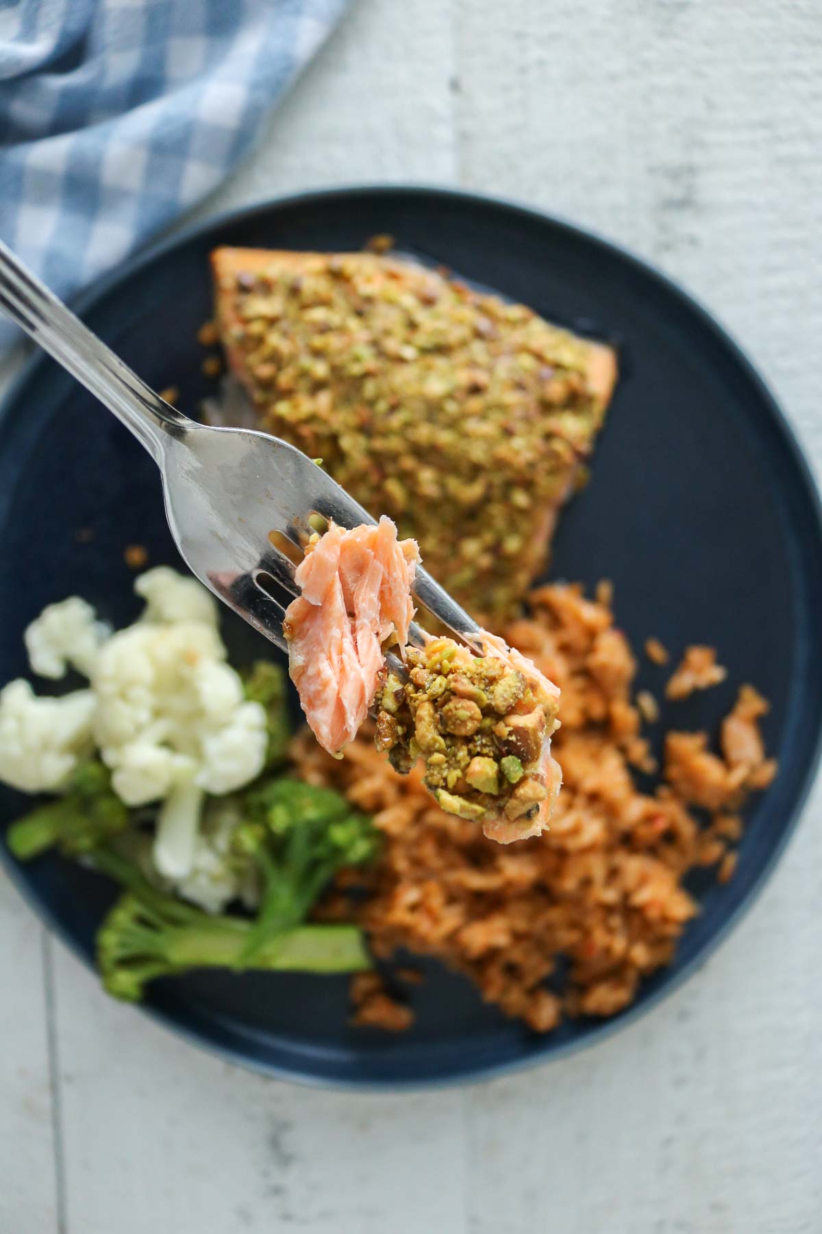 Forkful of pistachio-topped arctic char from a plate.