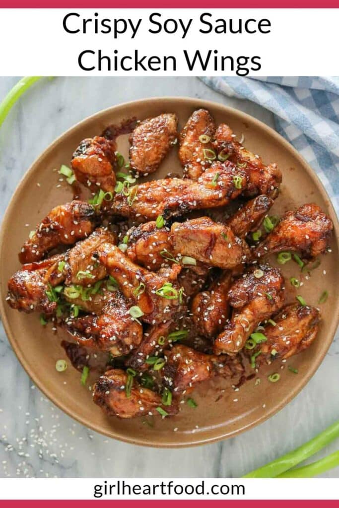 Crispy soy sauce chicken wings on a plate garnished with green onion and sesame seeds.