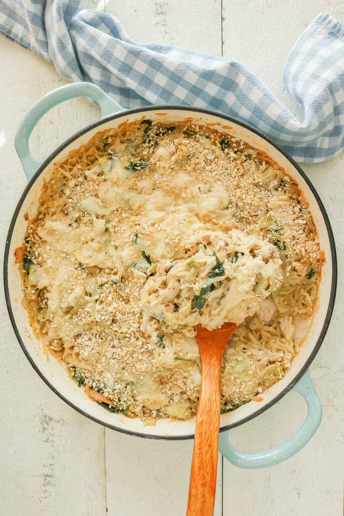 Pan of orzo bake with a wooden serving spoon.