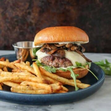 Mushroom Swiss burger and fries on a plate with truffle mayo.