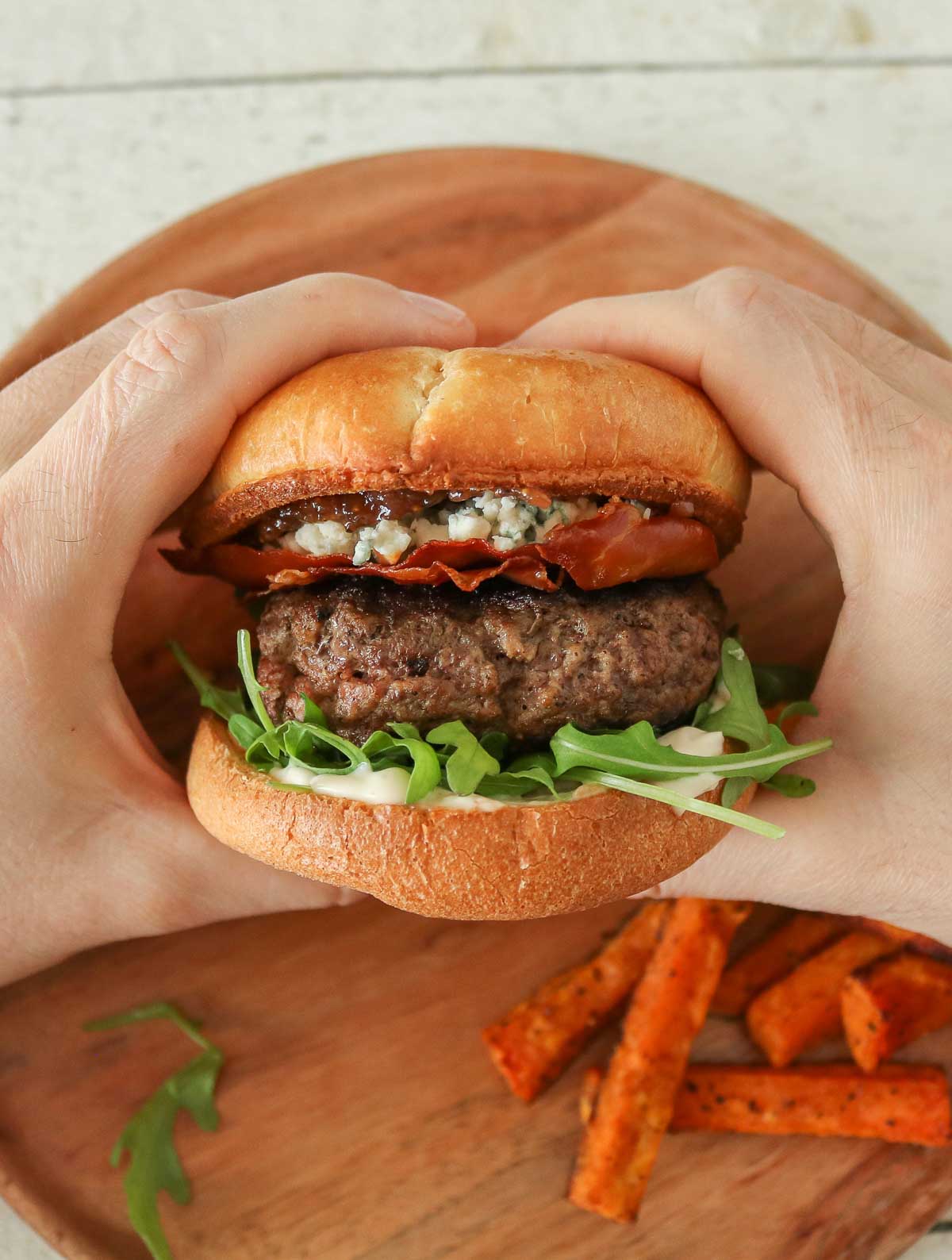 Two hands holding a homemade hamburger.