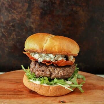 Prosciutto and blue cheese burger on a wooden plate.