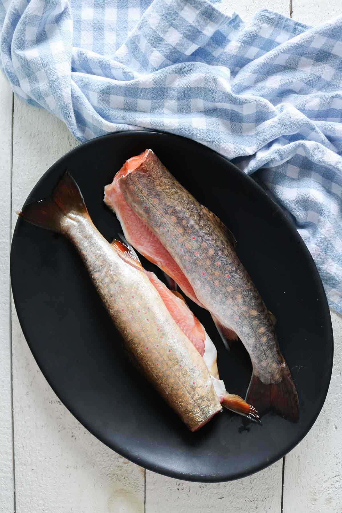 Two uncooked trout on a platter.