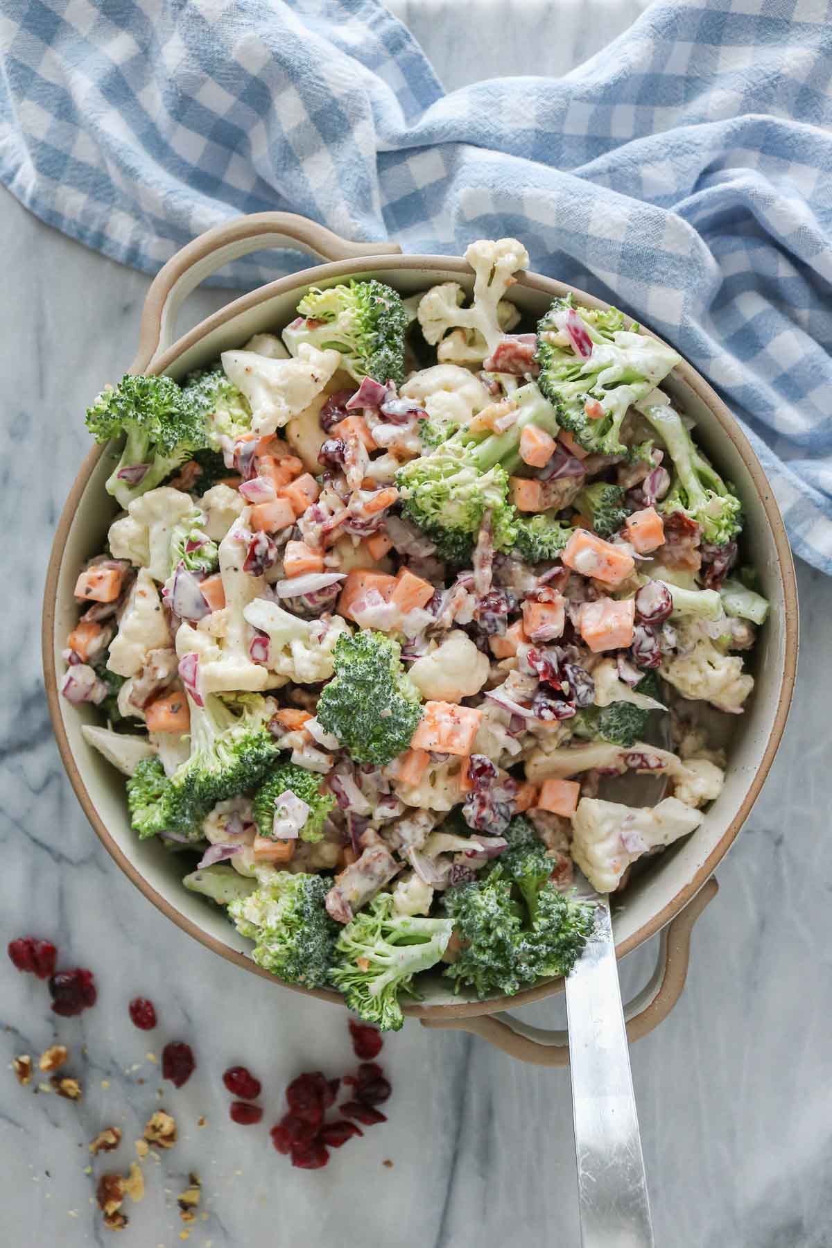 Cauliflower broccoli salad in a serving dish with a serving spoon.