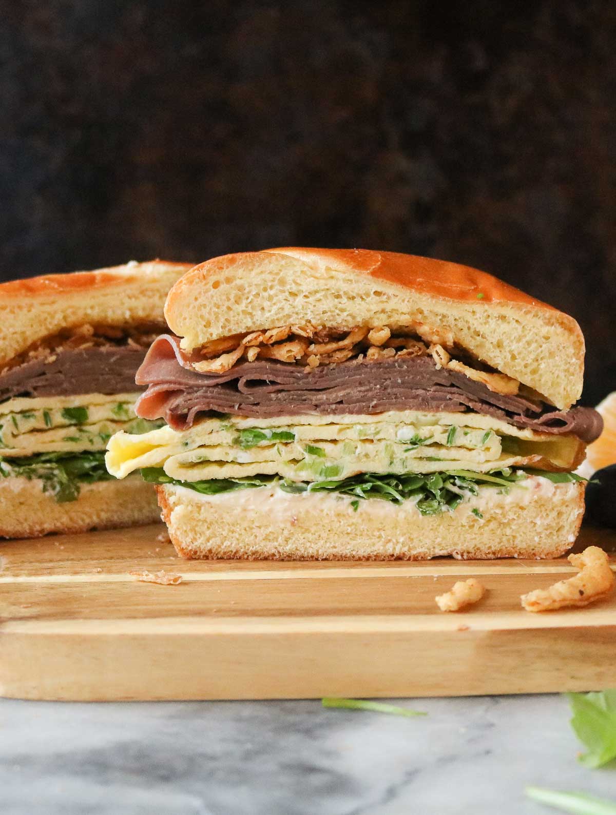 Two halves of a roast beef and egg sandwich.