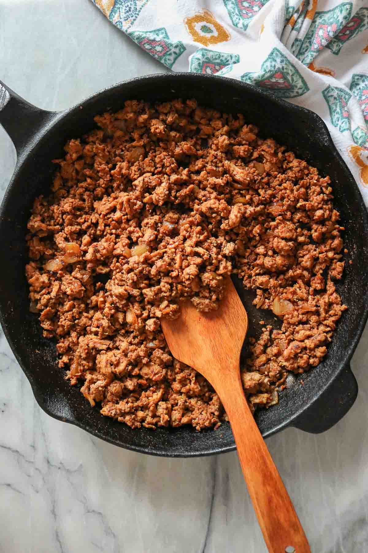 Ground chicken taco meat in a skillet with a wooden spoon.