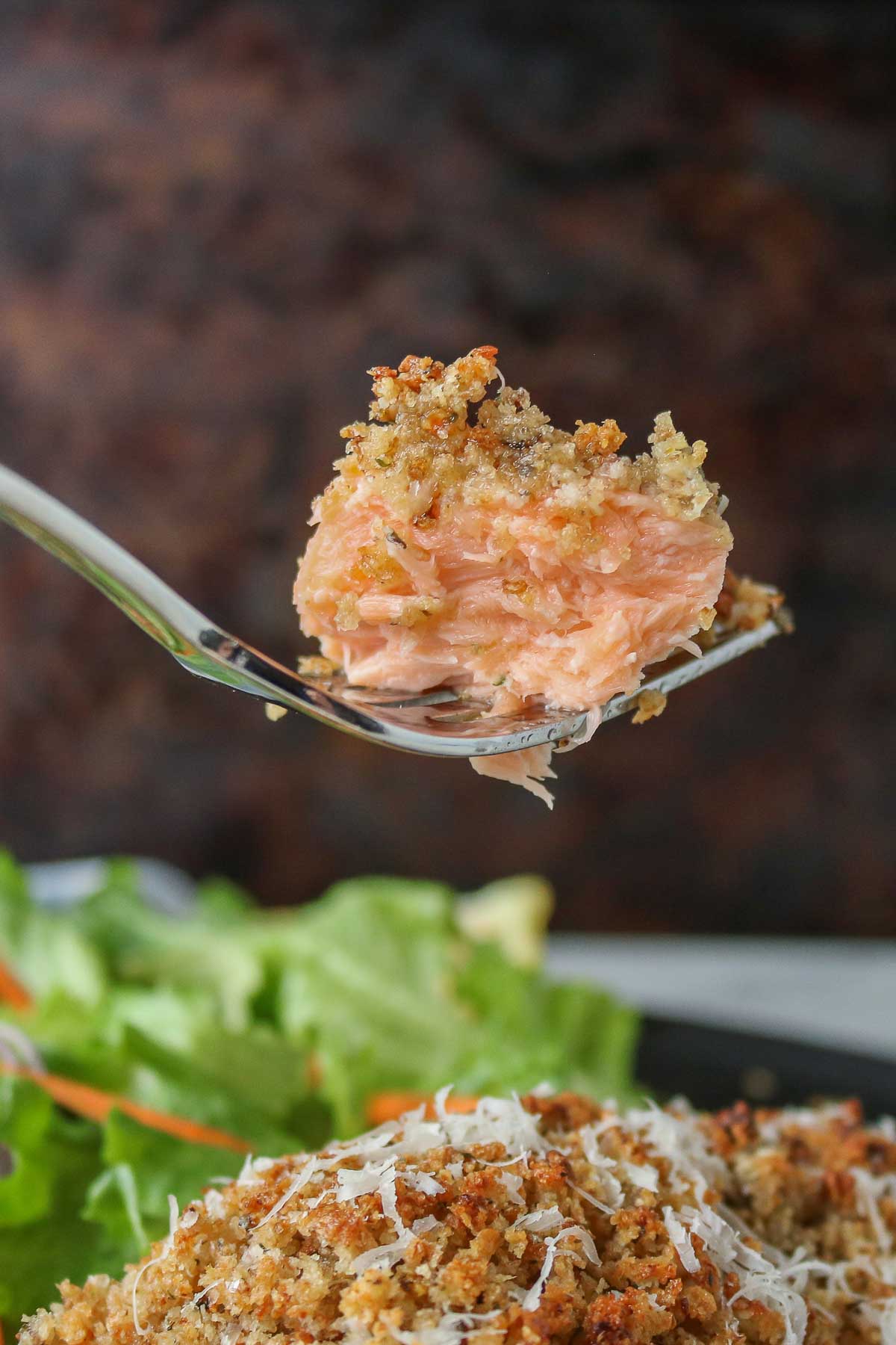 Forkful of baked salmon from a plate.