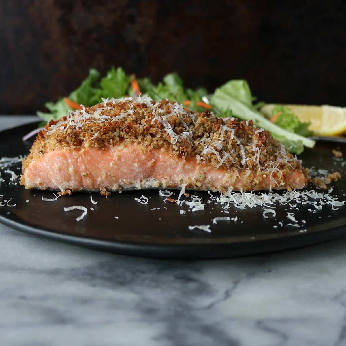 Side profile of a portion of baked salmon on a plate.