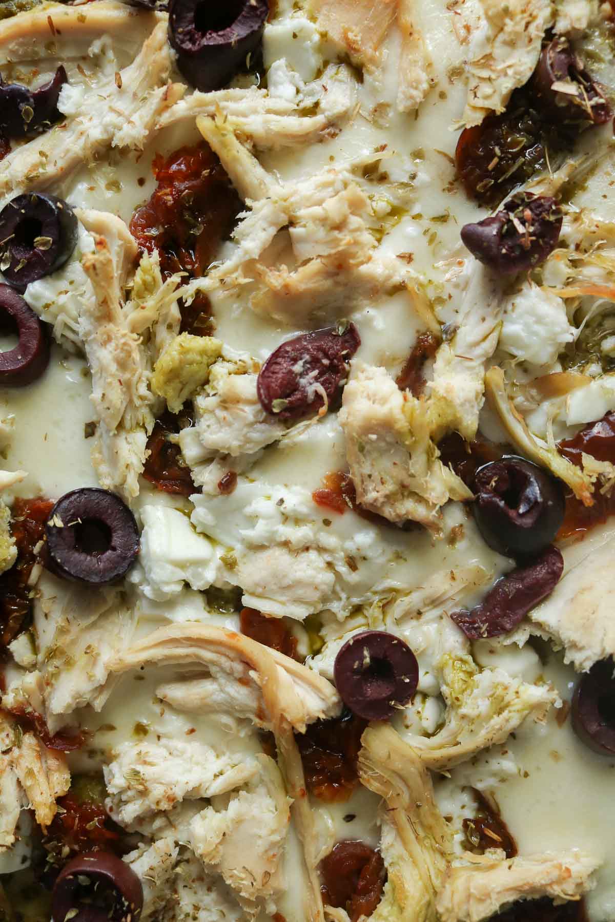 Tight close-up of a chicken pesto pizza.