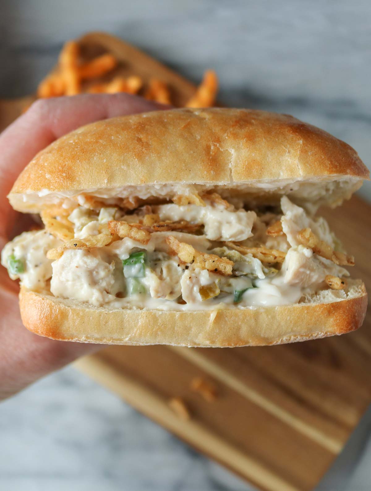 Hand holding a jalapeno chicken salad sandwich.