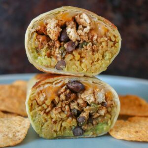 Stack of two halves of a ground chicken burrito on a plate.