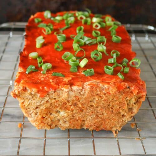 Buffalo chicken meatloaf on a cooling rack garnished with green onion.